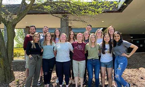 Group photo of students outdoors beside a tree